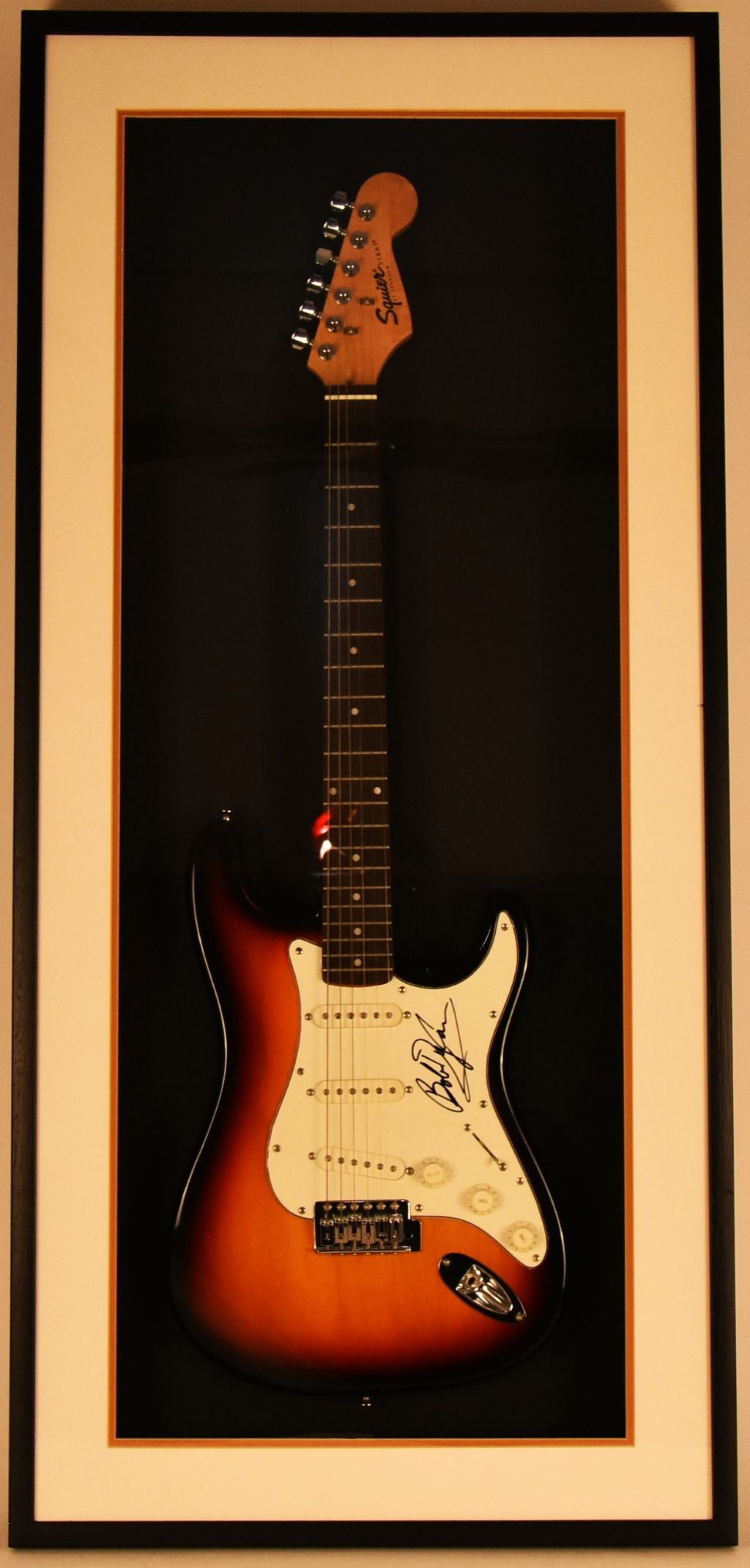 Bob Dylan interest; A framed Stratocaster electric guitar, labeled Squire by Fender, bearing ink signature to the scratch plate. Halls Fine Art Modern Art 9th July Shrewsbury